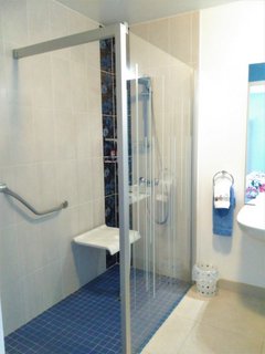 Rose view of walk in shower with seat down and hand rail
